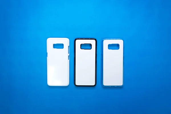 Back view of smartphone cases on vivid blue paper background. Three phone cover or protector for your design. ( Black , white , transparent )