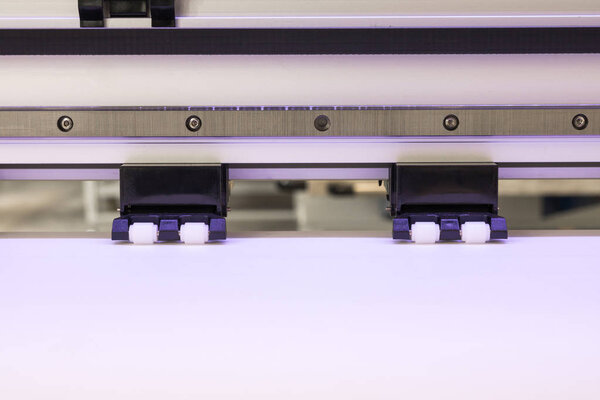 Blank paper roll and wheel in large printer format inkjet machine for industrial business.