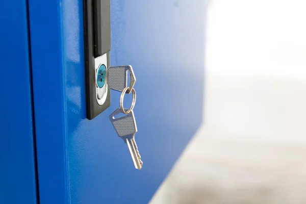 Blue locker and key chain in school gym. Modern metal cabinets and copyspace for your design.