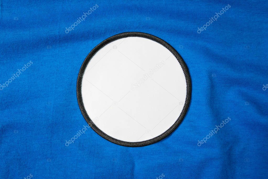 Blank arm patch on blue sport shirt. White team logo and emblem for your montage or edit.