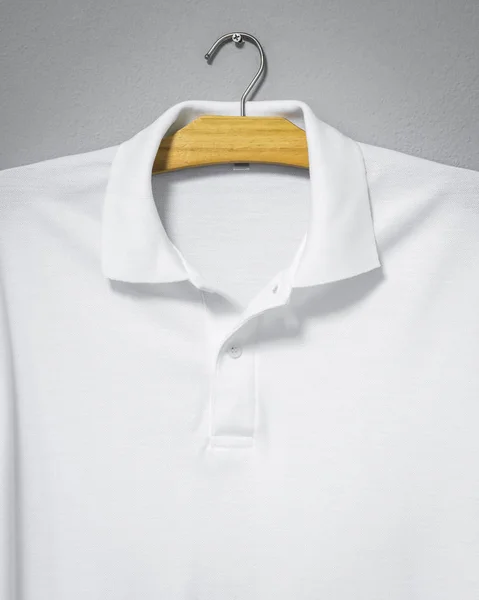 セメントの壁に掛かっている白いシャツのクローズアップ 印刷用のブランクTシャツ — ストック写真