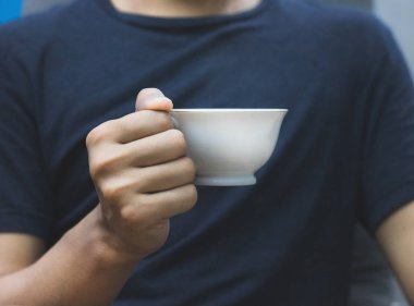 Koyu renk gömlek arka planında elinde kahve bardağı tutan adam. Tasarım için Vintage kupalar.