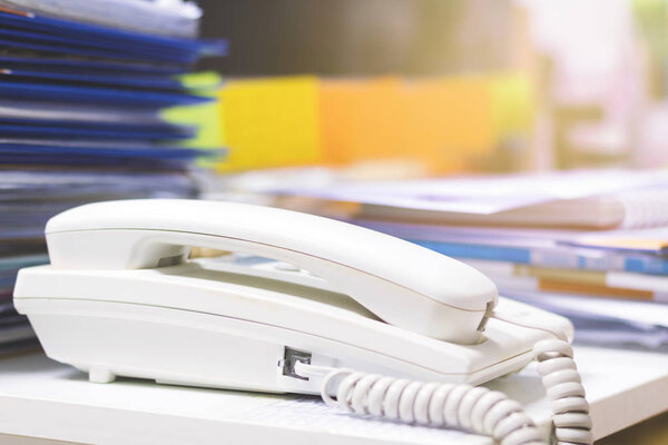 Close up of phone and a lots of unfinished documents on office desk.