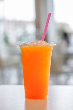 Beyaz masa arka plan üzerinde plastik cam ve tüp portakal suyu. Şifa için C vitamini içecek.