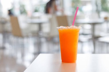 Beyaz masa arka plan üzerinde plastik cam ve tüp portakal suyu. Şifa için C vitamini içecek.