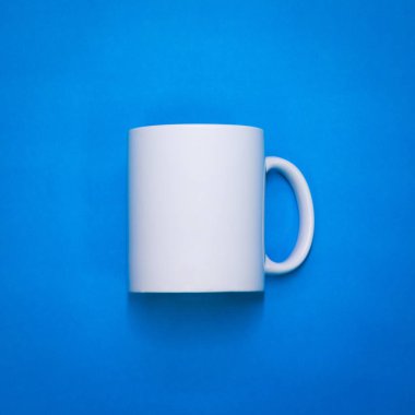 Beyaz kahve fincanı mavi kağıt arka planda. Tasarımınız için bir bardak şablonu. Metin, resim ve logo koyabilirsin. Ön veya yan görünüm.