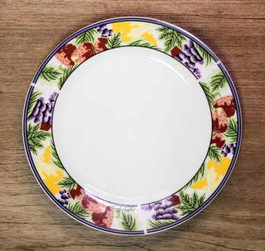 Ahşap masa arka plan üzerinde güzel seramik çanak. Meyve desen tarzında tasarım plakası.