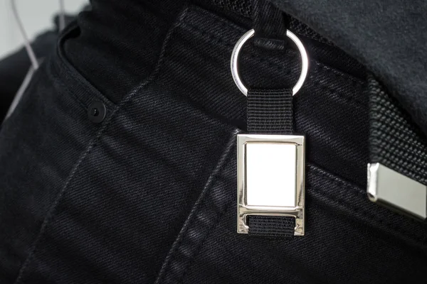 Steel key ring hanging on black jeans. Blank key chain for your design. Souvenir or accessory. Can put text, image, and logo.