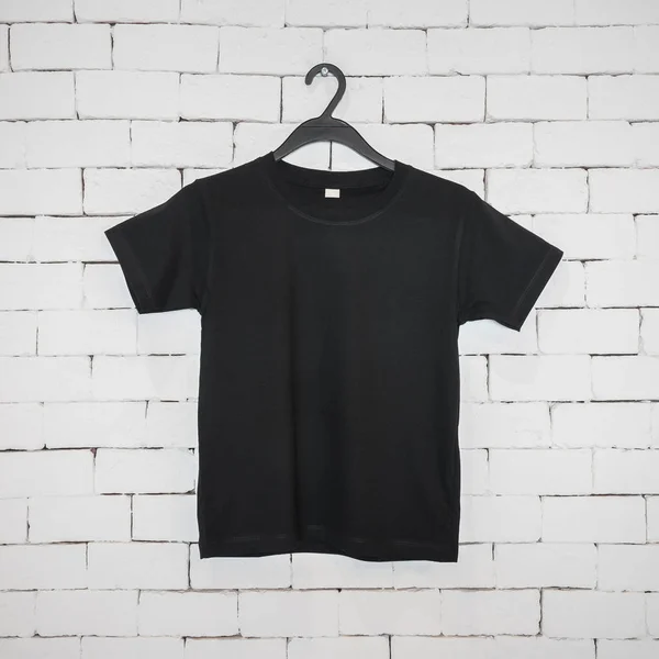 Black hanging shirt on brick wall in modern concept advertising. Blank Cotton uniform for your design.