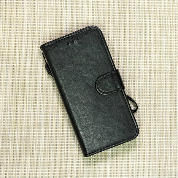 Black leather phone case on weave background. Fashion mobile phone cover.