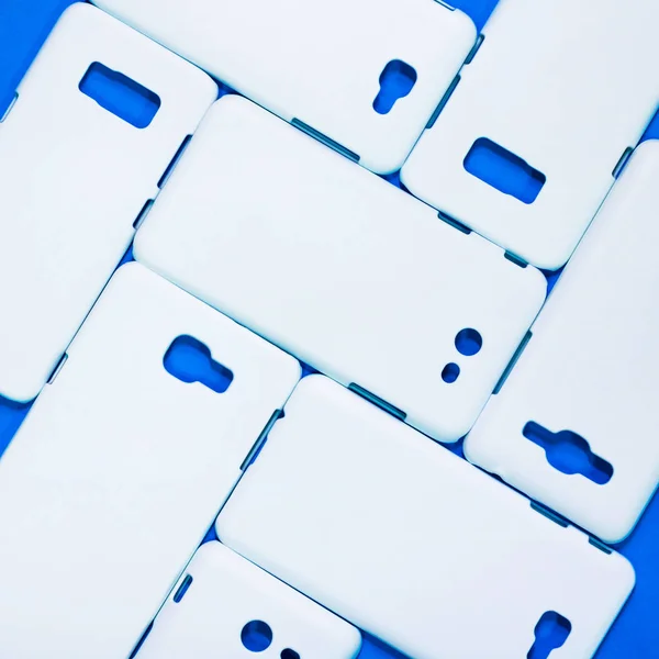 White phone cases on vivid blue background. Mobile cases or smartphone protector for your design.