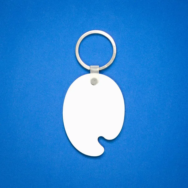 White key ring on blue background. Key chain for your design. Hanging accessory or souvenir. ( Color tray shape )