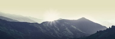 Gizemli arka planda, sabah vakti sisli dağların panorama manzaraları. Doğa, gün batımından önce dağın arkasında. Doi Phu Kha Tayland Ulusal Parkı.