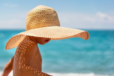 Sahilde hasır şapkalı sevimli çocuk