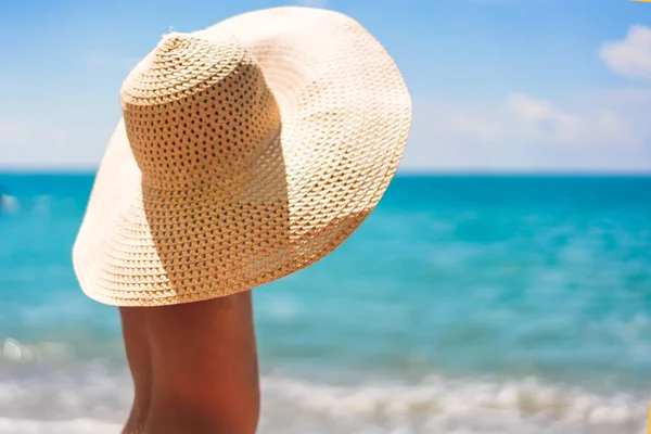 Schattige jongen in een stro hoed op het strand op zoek naar de zee — Stockfoto