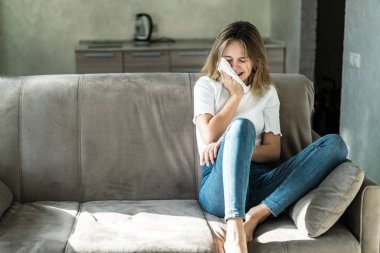 Üzgün genç kadın evde kanepede oturan ve ağlıyor, o depresif ve yalnız