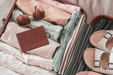 Giyim, aksesuar ve pasaport, seyahat ve tatil konsepti ile açık yolcu çantası