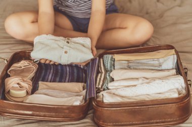 Kadın bavulu, gezmeye ve cep telefonuyla konuşmaya hazırlanıyor. Seyahat valizi hazırlama konsepti