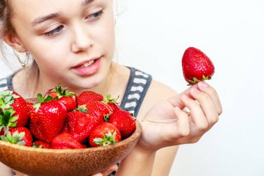 Genç bir kadın elinde bir kase çilek tutuyor.