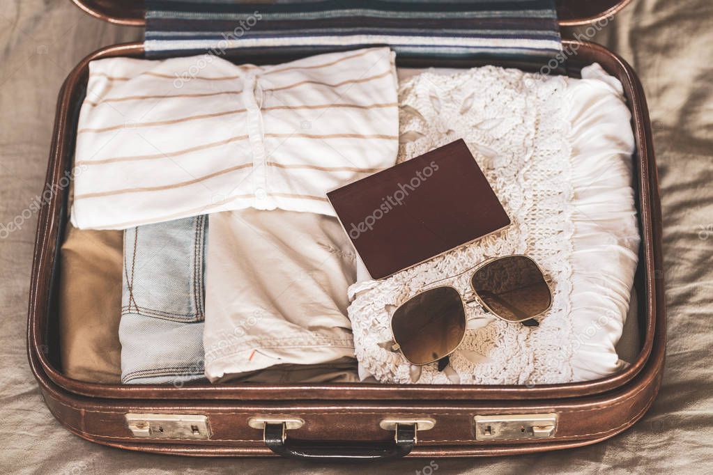 Open traveler's bag with clothing, accessories and passport, travel and vacations concept