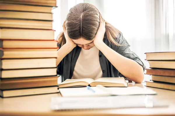 Stressed college student tired of hard learning with books in ex