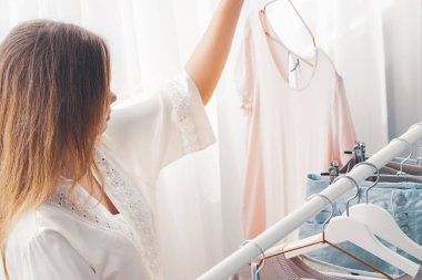 Kadın seyahat için hangi giysi paketi seçebilir. Giyim, moda, stil ve insanlar kavramı-kadın ev gardıropla giysi seçimi. 