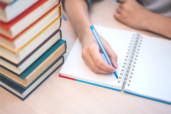 Joven estudiante sentado en el escritorio en casa estudiando y leyendo — Foto de Stock