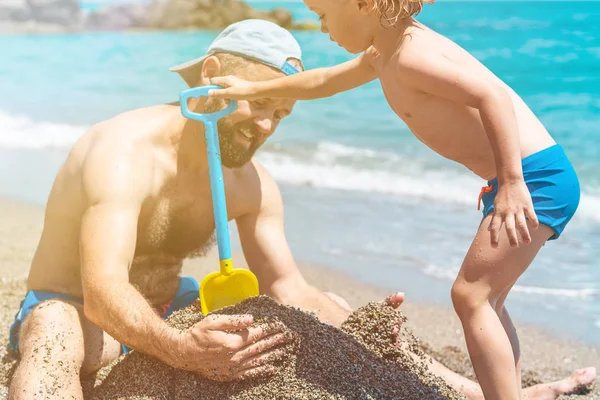 Feliz pai e filho brincando juntos na areia na praia tropical — Fotografia de Stock