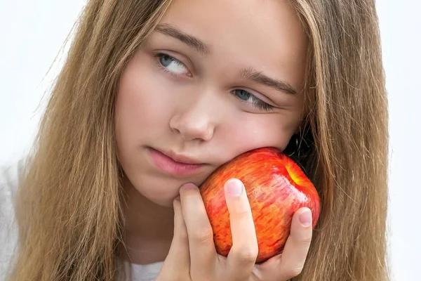 Girl in white shirt , holding red apple in the hands near the cheek — Stock Photo, Image