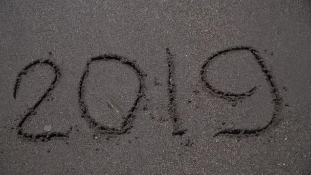 A inscrição 2020 na areia é lavada pela onda do mar. Saudações de Ano Novo. Feriados. presente . — Vídeo de Stock
