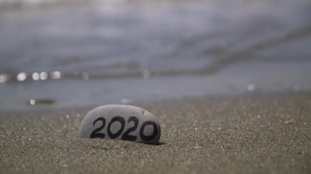 Inscripción 2020 en una piedra lavada por la ola del mar saludos de año nuevo regalo de vacaciones — Vídeo de stock