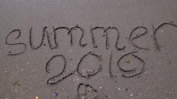 Надпись летом 2019 года на песке смытом морской волной новогодний подарок — стоковое видео