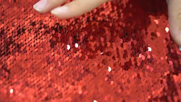 Lantejoulas douradas e vermelhas para coser em uma mão em um fundo branco — Vídeo de Stock