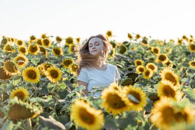 Genç ve güzel bir kadın Ayçiçeği tarlasında eğleniyor