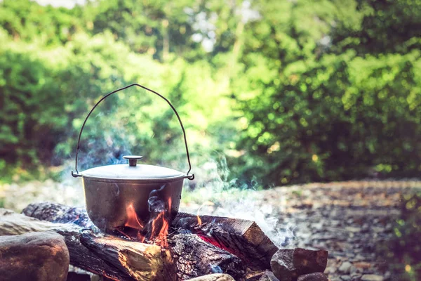 Resor, turism, picknick matlagning, matlagning i en kittel på elden — Stockfoto