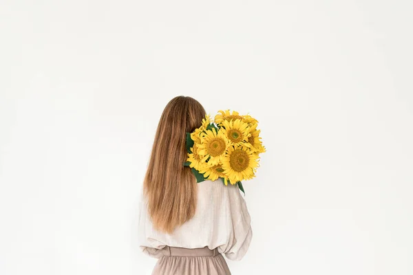 Hermosa joven en vestido de lino con flores de girasol ramo. —  Fotos de Stock