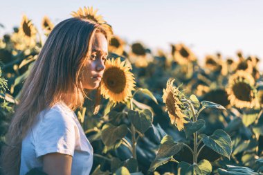Genç ve güzel bir kadın Ayçiçeği tarlasında eğleniyor