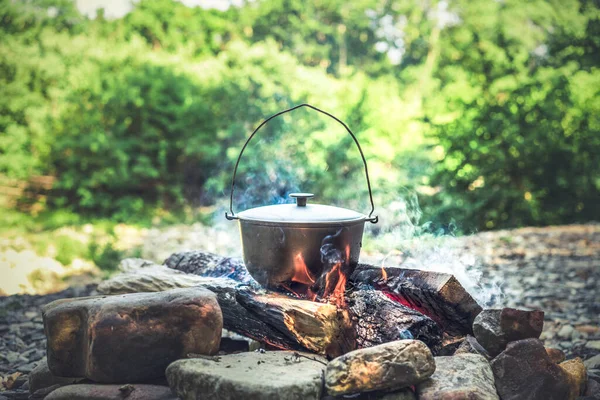 Resor, turism, picknick matlagning, matlagning i en kittel på elden — Stockfoto