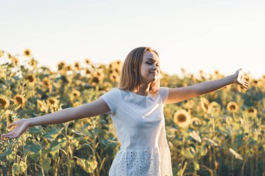 Genç ve güzel bir kadın Ayçiçeği tarlasında eğleniyor