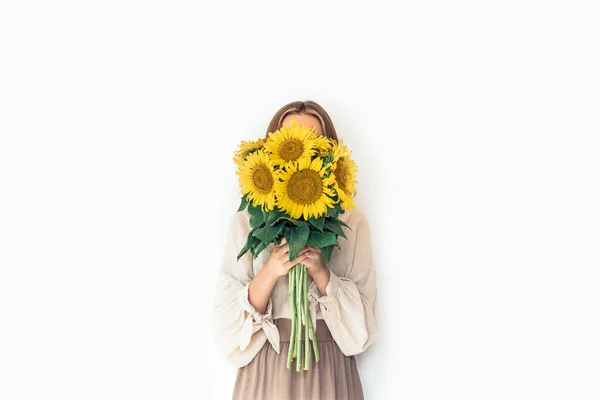 Krásná mladá žena v lněných šatech drží slunečnice kytice. — Stock fotografie