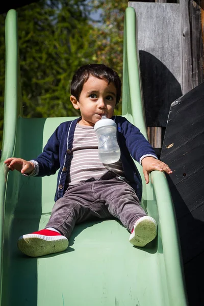 Oyun alanında açık oynayan bir süt şişesi ile sevimli bebek