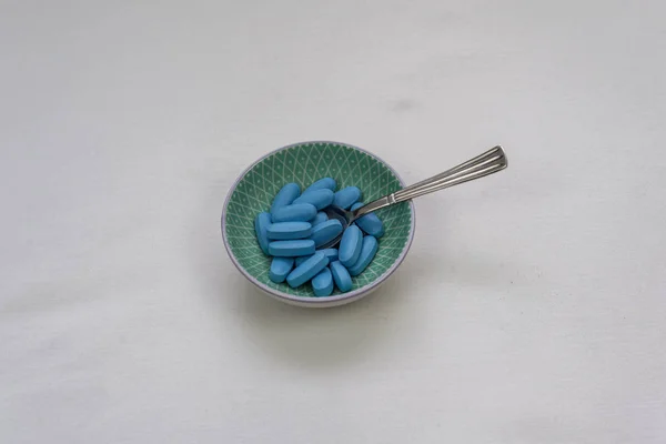 Small bowl with blue pills and spoon — Stock Photo, Image