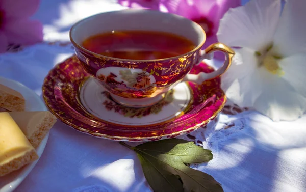 Vintage Cup Met Thee Wit Tafelkleed Paarse Bloemen Close — Stockfoto