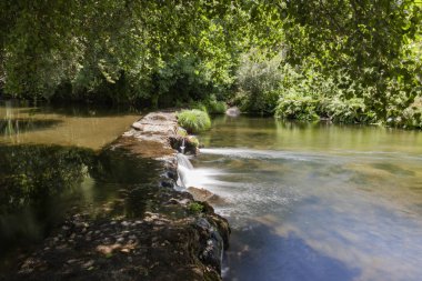 Portekiz'de bir nehirde, insan yapımı baraj geçerken küçük şelaleler oluşturan kristal su,.