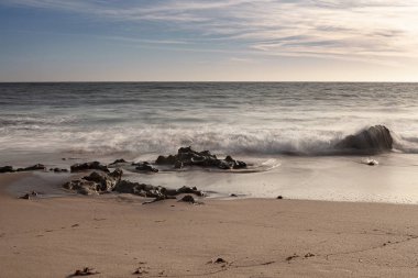 A erosao fragmenta a rocha em pequenos graos de areia e vai deixando para tras partes de rocha no meio do areal e na zona de rebento das ondas, o que produz lindas fotografias, fotografia tirada na Praia da Ilha em Porto Covo, Portekiz, Europa