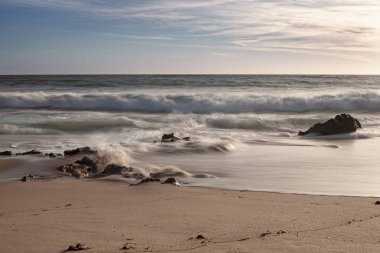 A erosao fragmenta a rocha em pequenos graos de areia e vai deixando para tras partes de rocha no meio do areal e na zona de rebento das ondas, o que produz lindas fotografias, fotografia tirada na Praia da Ilha em Porto Covo, Portekiz, Europa