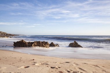 A erosao fragmenta a rocha em pequenos graos de areia e vai deixando para tras partes de rocha no meio do areal e na zona de rebento das ondas, o que produz lindas fotografias, fotografia tirada na Praia da Ilha em Porto Covo, Portekiz, Europa