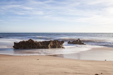 A erosao fragmenta a rocha em pequenos graos de areia e vai deixando para tras partes de rocha no meio do areal e na zona de rebento das ondas, o que produz lindas fotografias, fotografia tirada na Praia da Ilha em Porto Covo, Portekiz, Europa