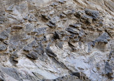 Kayalık duvarın yüzeyi, en sert kayaparçalarının öne çıktığı, sağlamlıklar oluşturan farklı sertliklere sahip. Arka plan olarak kullanılabilir.