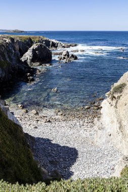 Yuvarlak taşlı güzel sahil, Alentejo, Portekiz, Avrupa 'daki balıkçıların rotasındaki kayalardan korunuyor..